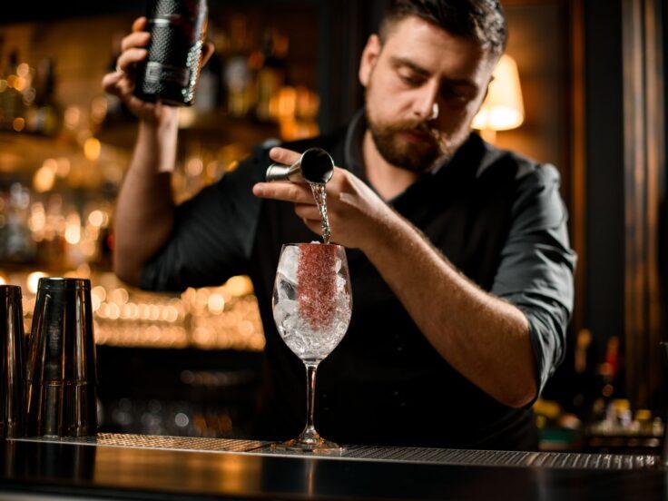 Bartender utilizza shaker e jigger durante la preparazione di un cocktail